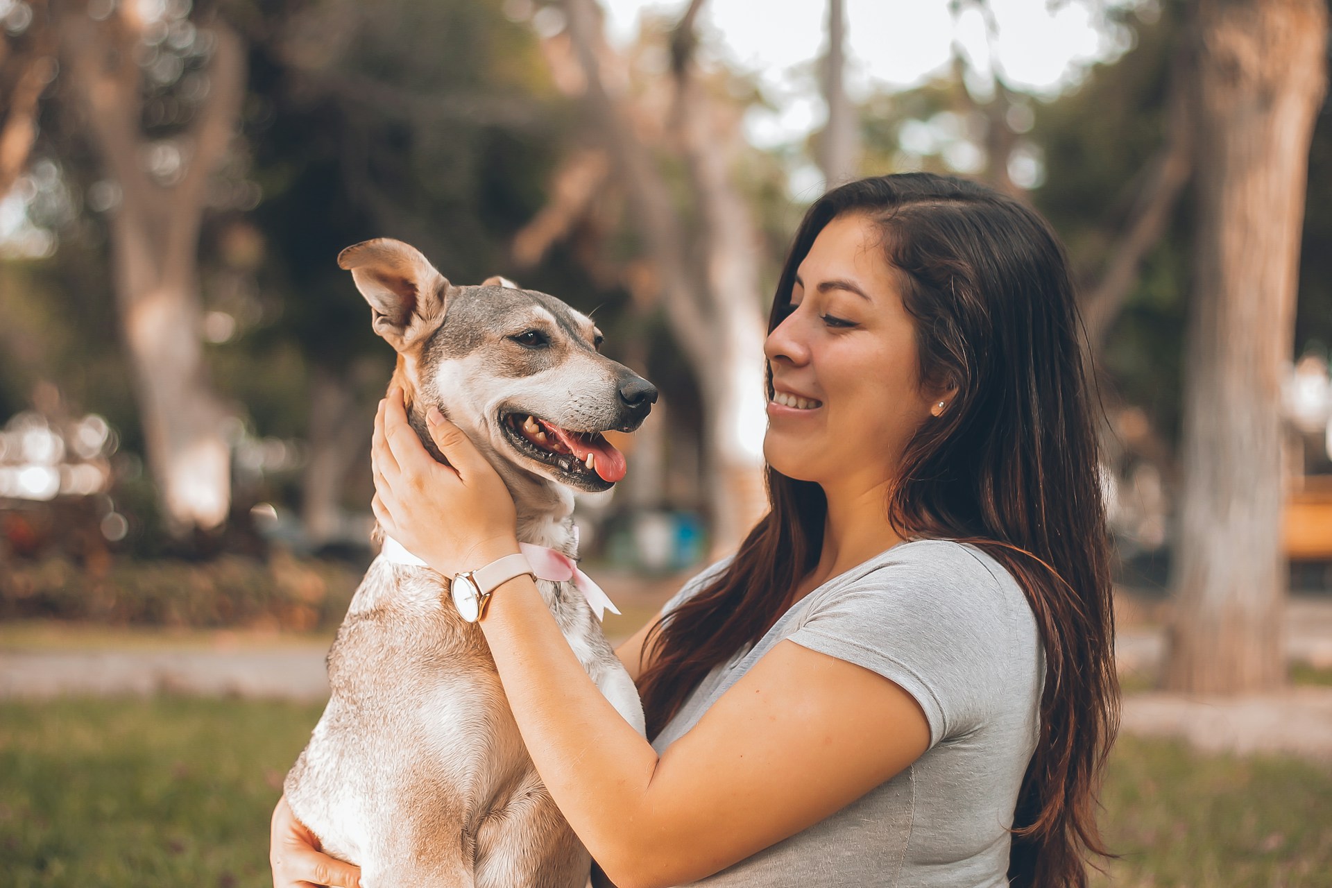woman smiling and holding dog in a park